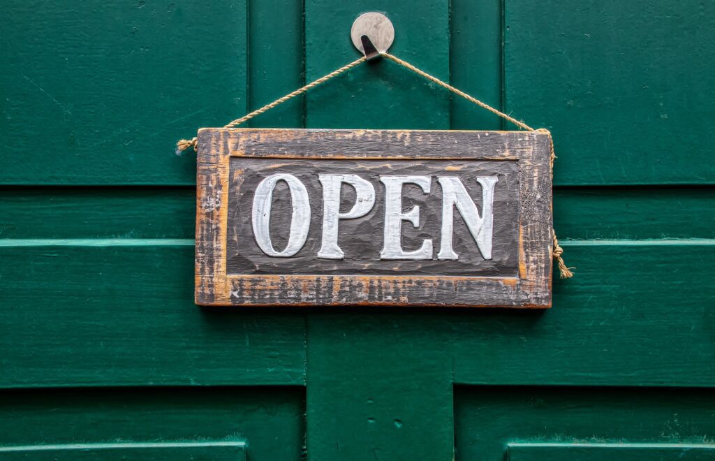 OPEN - Schild mit Aufdruck Geöffnet an einer Holztüre