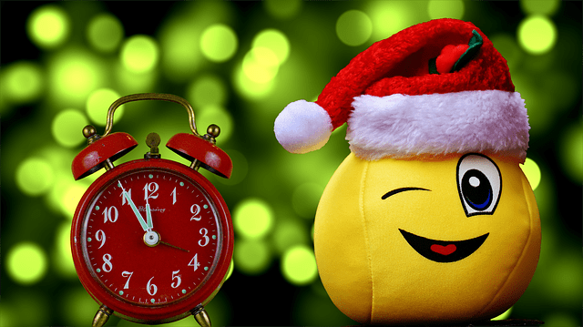 Ein Wecker mit einer Uhr. Diese zeit 5 vor 12 an. Daneben ein gelber Ball, mit Nikolausmütze und einem freundlichen Gesicht.